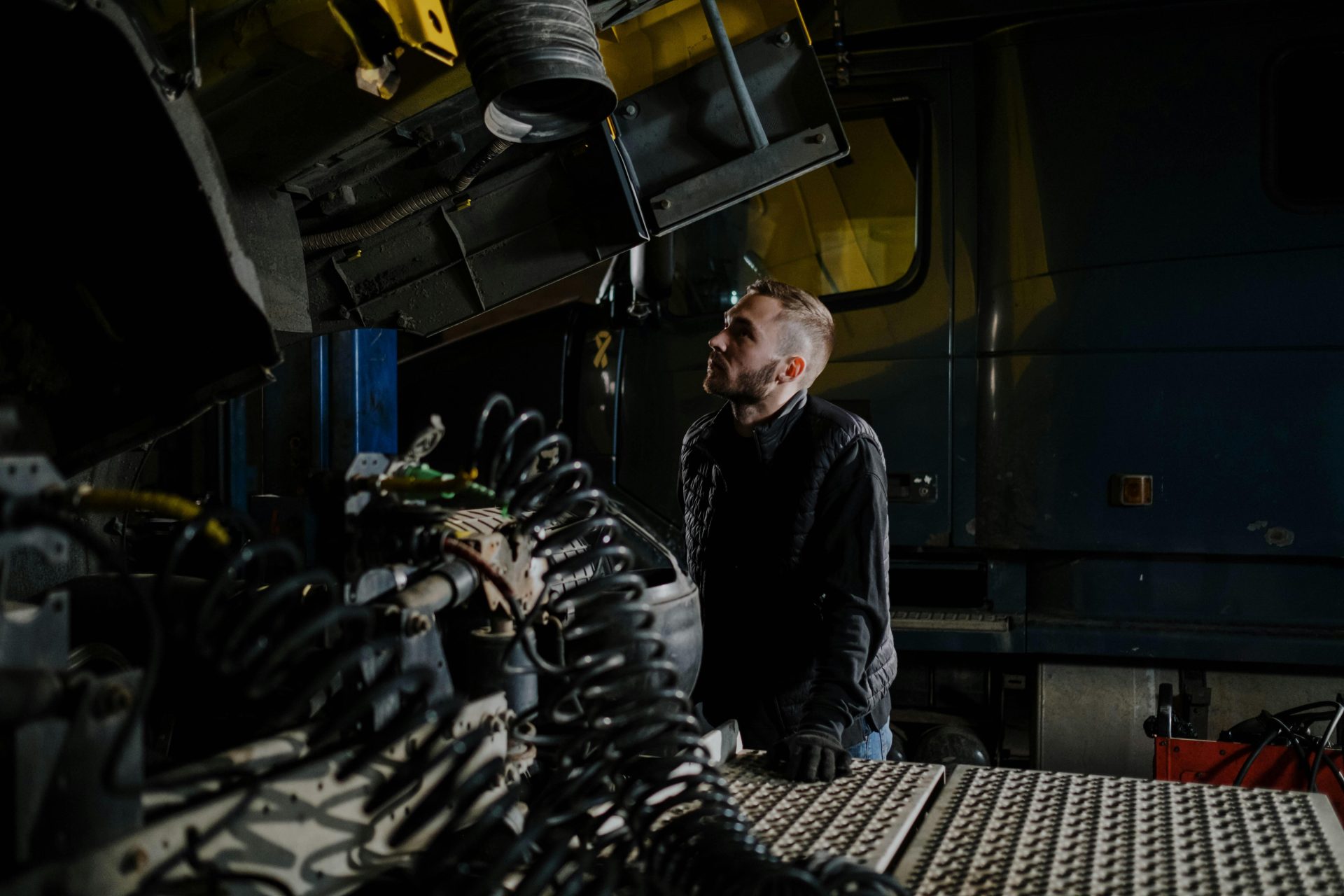 Un mécanicien de camion examine attentivement un moteur à l'intérieur d'un garage.